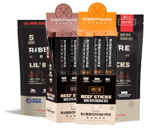 A display box of Ribbon Wire Ranch Beef Sticks made with organic beef, showing multiple individual stick packages in front of larger black and orange retail pouches on a white background.